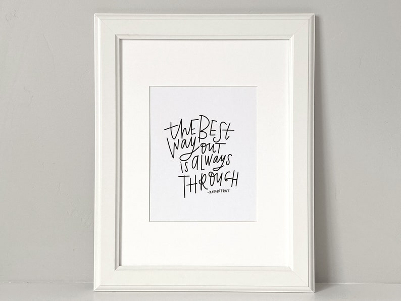 Puede incluir: Una impresi&oacute;n enmarcada en blanco con caligraf&iacute;a negra que dice "The best way out is always through" con el nombre del autor "Robert Frost" debajo.