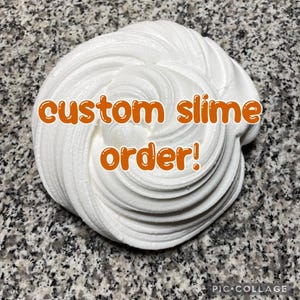 May include: A close-up of a swirl of white slime with the text "custom slime order!" in orange. The slime is on a speckled gray surface. The image is taken from a close-up angle.