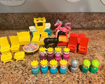 May include: A collection of colorful plastic toy figures and furniture. Includes yellow chairs, a table, a horse, a dragon, and several toy people with crowns. The toys are arranged on a speckled countertop.