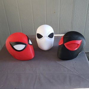 May include: Three Spider-Man masks, one red, one black, and one white. The masks have black eye holes and red accents.