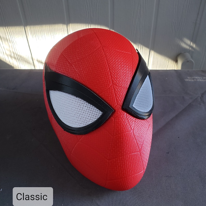 May include: A red and black Spider-Man mask with a textured surface and white mesh eye holes. The mask is labeled "Classic".
