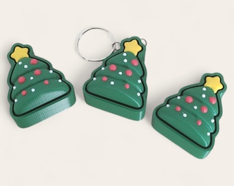 May include: Three green Christmas tree keychains with a yellow star on top, red and white ornaments, and a silver keyring. The keychains are a festive holiday decoration.