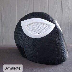 May include: Black and white 3D printed mask with a spiderweb design and a white eye piece. The mask is labeled "Symbiotic" at the bottom.