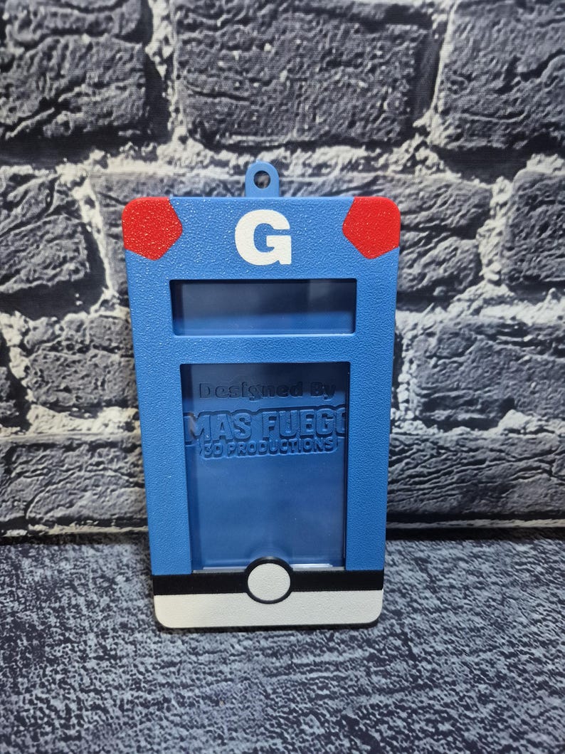 May include: A blue, rectangular 3D-printed item with a white base and a white circle. It has a red accent on each top corner and a white "G" in the center. The text "Designed By MAS FUEGO 3D PRODUCTIONS" is visible.