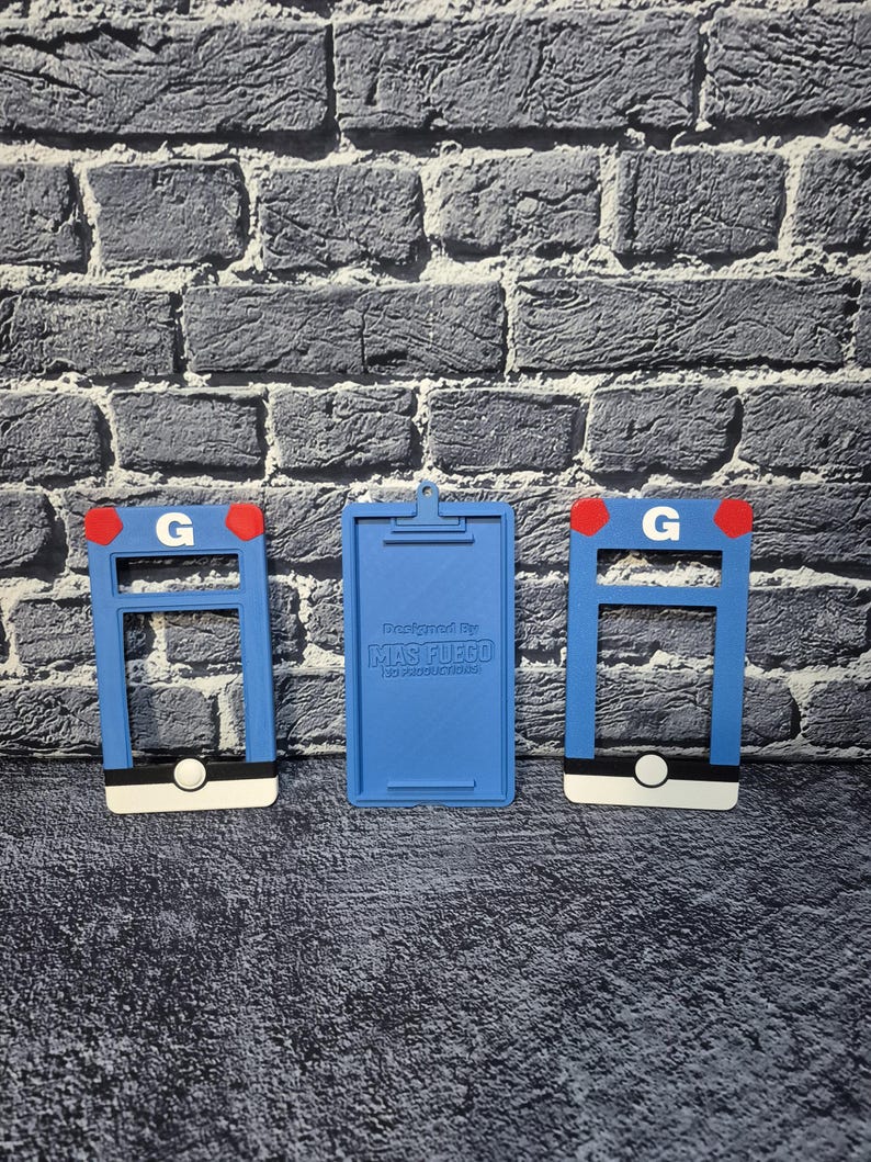 May include: Three blue 3D-printed items. Two have a rectangular frame with a white base, a black stripe, and a red accent. The third is a blue clipboard with the text "Designed By MAS FUEGO".
