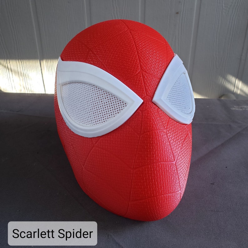 May include: A red and white Spider-Man mask with a textured surface. The mask has a white mesh over the eyes.