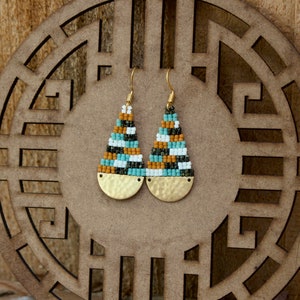 May include: A pair of teardrop-shaped earrings with gold-toned metal accents. The earrings are made with small, colourful beads in shades of brown, white, green, and blue.