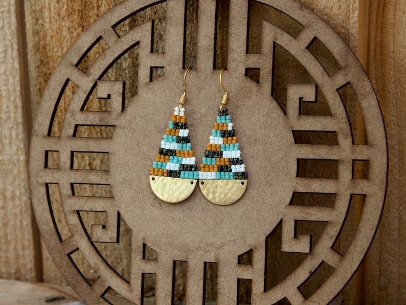 May include: A pair of teardrop-shaped earrings with gold-toned metal accents. The earrings are made with small, colourful beads in shades of brown, white, green, and blue.