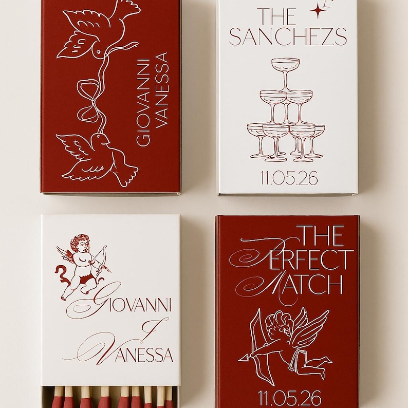 May include: Four matchboxes with red and white designs. Two boxes are red with white illustrations of doves and an angel with a bow and arrow. Two boxes are white with champagne glasses and the text "The Sanchezs" and "Giovanni Vanessa".