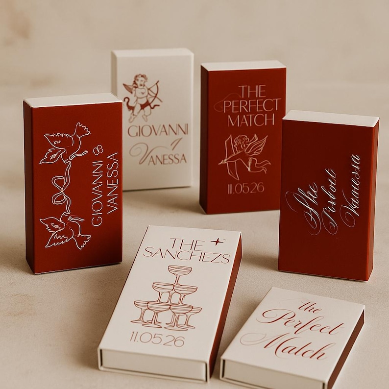 May include: A collection of matchboxes in red and white, featuring various designs and text. Some boxes display names like "Giovanni & Vanessa" and "The Sanchezs," while others have phrases such as "The Perfect Match" and dates like "11.05.26."