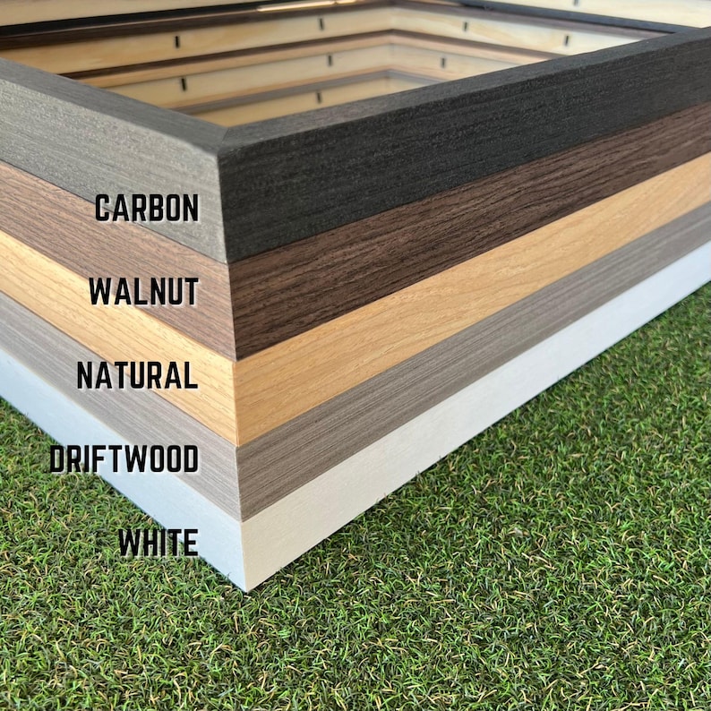 May include: A stack of five rectangular picture frames with distinct finishes labeled Carbon, Walnut, Natural, Driftwood, and White. Each frame features a wood grain texture and a mitered corner design, showcasing a variety of color options.