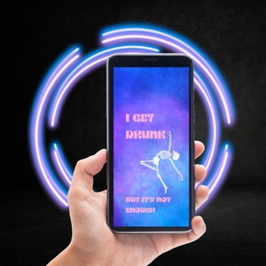 May include: A black smartphone displaying a purple and blue galaxy-themed wallpaper with the text "I GET DRUNK BUT IT'S NOT ENOUGH" and a skeleton illustration. The phone is held in a hand against a dark background with a neon circle.