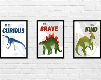 May include: Three framed prints with dinosaur illustrations and motivational messages. The first print features a blue dinosaur with the message "Be Curious". The second print features a green dinosaur with the message "Be Brave". The third print features a green dinosaur with the message "Be Kind".
