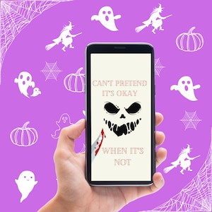 Könnte beinhalten: Ein Smartphone mit einem schwarzen Bildschirm, auf dem eine Halloween-Grafik mit dem Text "Can't pretend it's okay when it's not" angezeigt wird. Das Telefon wird in einer Hand vor einem lila Hintergrund mit weißen Spinnweben und Geistern gehalten.