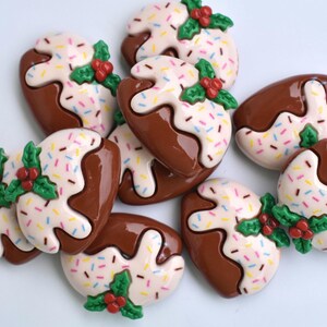 May include: A group of nine brown and white Christmas pudding-shaped buttons with green holly and red berries. The buttons are decorated with white icing and colorful sprinkles.