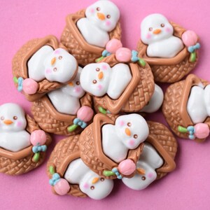 May include: A collection of brown wicker baskets with white snowmen inside. Each basket has pink and blue flowers and green leaves.