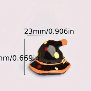 May include: A miniature black witch hat with orange and yellow polka dots and trim. The hat is 0.906 inches wide and 0.669 inches tall, perfect for Halloween decorations or crafts.