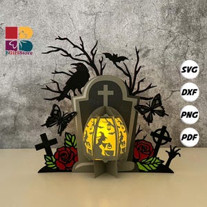 Puede incluir: Una manualidad de papel con temática de Halloween que presenta una lápida, un cuervo, murciélagos y mariposas. Una linterna de calabaza brillante está en el centro. El diseño incluye rosas rojas y cruces. La imagen tiene el texto "BGirlStore".
