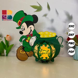 Könnte beinhalten: Ein St. Patrick's Day-Themen-Ausschnitt mit Mickey Mouse in grünem Outfit und Hut, neben einem Goldtopf. Eine leuchtende Laterne mit dem Wort "Lucky" und Kleeblatt-Designs ist ebenfalls vorhanden. Das Bild enthält SVG-, DXF-, PNG- und PDF-Dateioptionen.