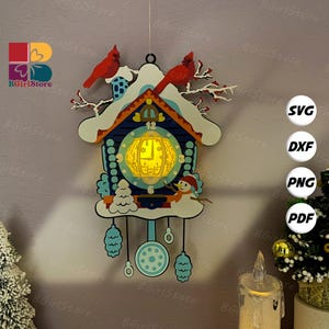 Puede incluir: Un reloj de cuco decorativo de madera con temática invernal. El reloj presenta un diseño de casa azul y blanco, un muñeco de nieve y dos pájaros cardenales rojos. El reloj tiene una esfera de reloj amarilla brillante.