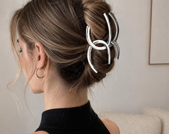 Pinza para el cabello de metal plateado, accesorio moderno y minimalista para moños y recogidos.
