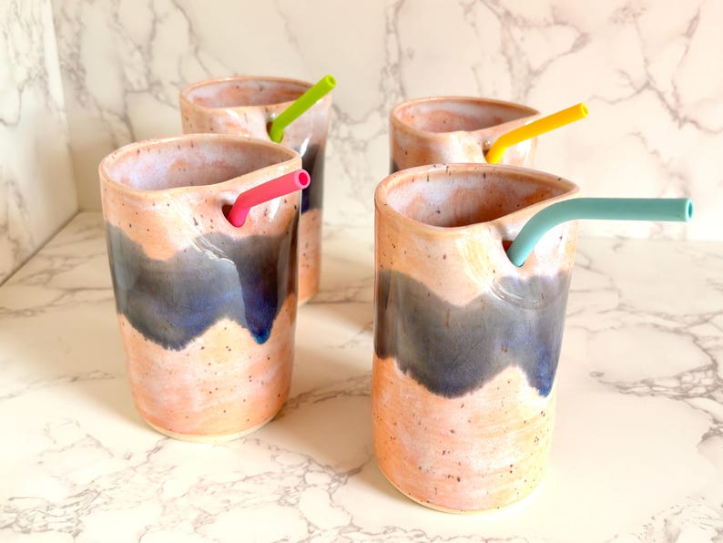 Puede incluir: Cuatro vasos de cer&aacute;mica hechos a mano con pajitas de silicona de colores. Los vasos tienen un dise&ntilde;o moteado en melocot&oacute;n y azul. Cada vaso tiene una pajita de diferente color: rosa, verde, amarillo y turquesa.