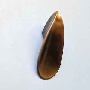 May include: A teardrop-shaped cabinet knob with a brushed bronze finish. The hardware features a smooth, curved surface that tapers to a point at the top and widens towards the base, showcasing a metallic texture with dark brown highlights.