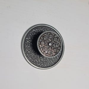 May include: A silver metal incense burner with a round, textured base and a removable top with a decorative, intricate design.