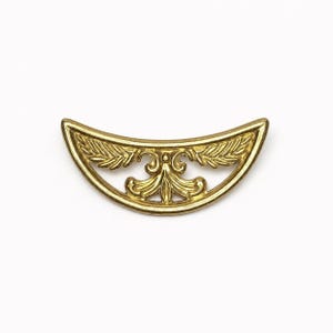 May include: A gold-colored, decorative furniture hardware piece. The curved, half-moon shaped piece features an openwork design with symmetrical leaf and floral motifs. The hardware is likely made of metal and is set against a white background.