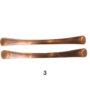 May include: Two copper-coloured metal drawer pulls with rounded ends. The pulls are arranged horizontally, one above the other.