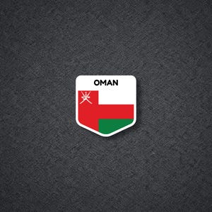 May include: A white, red, and green sticker with the word "OMAN" at the top. The sticker features the flag of Oman, with a red stripe, a white stripe, and a green stripe. The sticker is on a dark gray textured background.