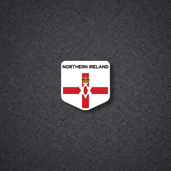 May include: A white, shield-shaped sticker displaying the Northern Ireland flag. The flag includes a red cross, a six-pointed star, and a crown. The text "NORTHERN IRELAND" is printed above the flag on the sticker.
