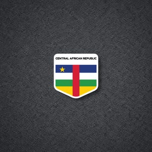 May include: A shield-shaped sticker featuring the flag of the Central African Republic, which consists of horizontal blue, white, green, and yellow stripes with a vertical red stripe in the center and a yellow star on the blue stripe.