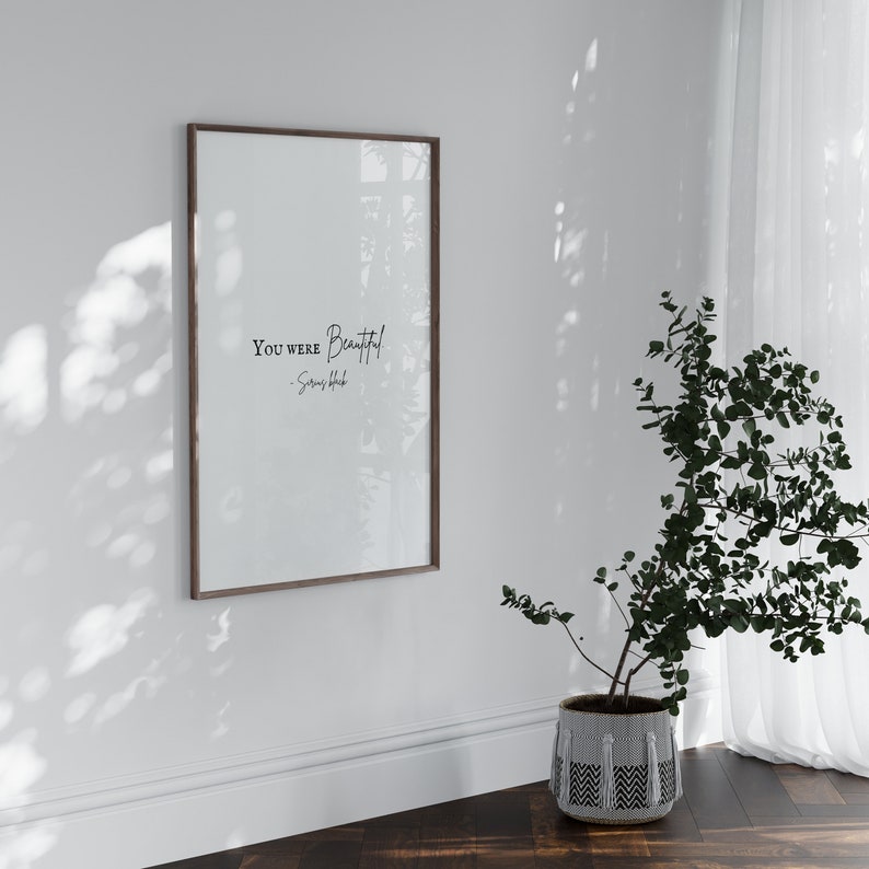 May include: A framed print with the text "You were beautiful" and the artist's name "Soren Hood" in a white room with a potted plant.