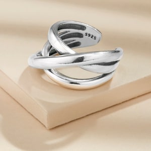 May include: Silver ring with a twisted design. The ring is marked with "S925" on the inside.