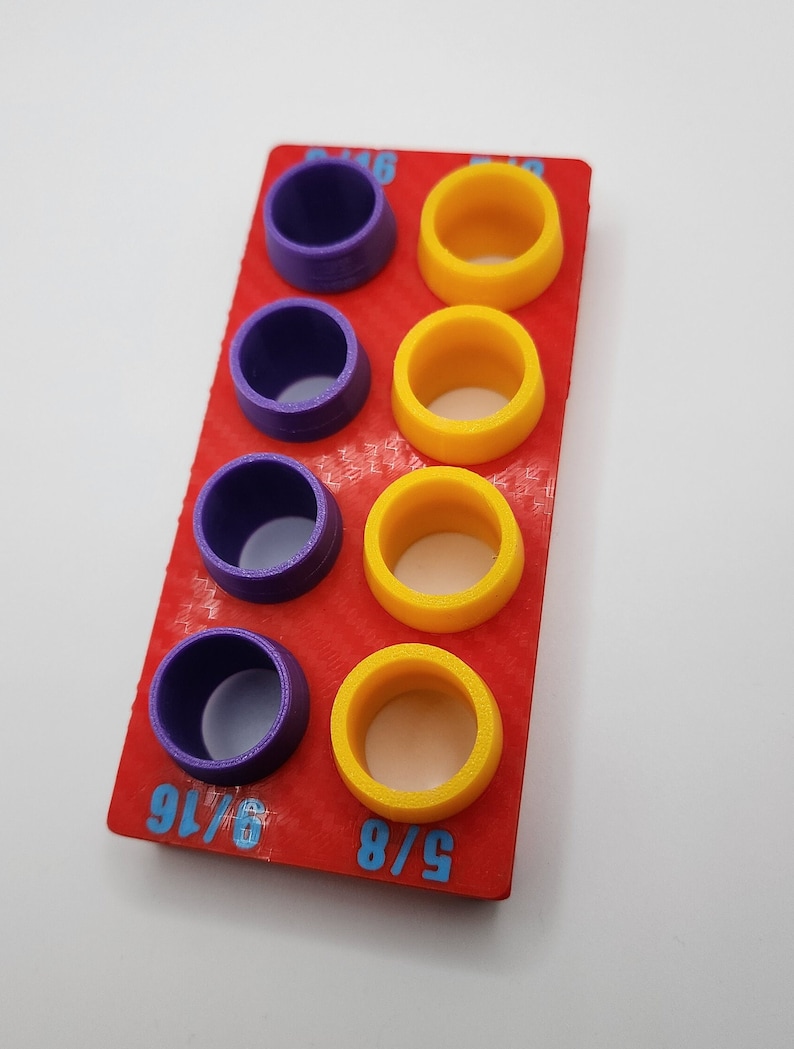 May include: A red plastic tool with purple and yellow rings. The tool is labelled with the fractions 5/8, 9/16, and 5/16.