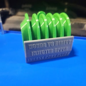K&ouml;nnte beinhalten: Ein 3D-gedruckter Einlasskr&uuml;mmer-Spacer aus gr&uuml;nem und grauem Kunststoff f&uuml;r einen Honda V6 mit direkter Einspritzung im oberen Einlasskr&uuml;mmer.