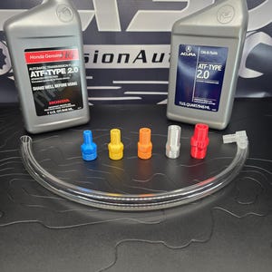 Peut inclure: Deux bouteilles grises de liquide de transmission automatique Honda et Acura ATF-Type 2.0, avec un tube transparent et cinq buses colorées. La bouteille Honda indique "SHAKE WELL BEFORE USING". La bouteille Acura indique "Oils & Fluids".