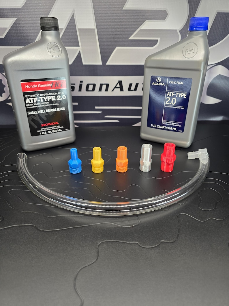 May include: Two gray bottles of Honda and Acura ATF-Type 2.0 automatic transmission fluid, with a clear tube and five colored nozzles. The Honda bottle reads "SHAKE WELL BEFORE USING". The Acura bottle reads "Oils & Fluids".