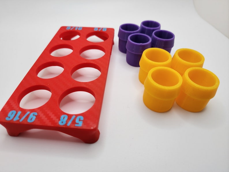 May include: A red plastic organiser with nine circular compartments for storing small items. The organiser has the text "5/8" and "6/16" printed on it. There are also six colourful plastic rings, four yellow and two purple, in the image.
