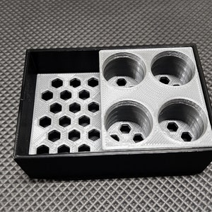 Peut inclure: Un organisateur noir et gris imprim&eacute; en 3D avec un motif en nid d'abeille et quatre compartiments circulaires. L'organisateur est con&ccedil;u pour contenir de petits objets, avec une surface textur&eacute;e.