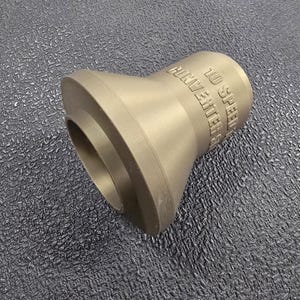 Puede incluir: Un convertidor de metal color bronce con el texto "10 Speed Converter" grabado en el lateral. El convertidor tiene una base acampanada y una parte superior cilíndrica.