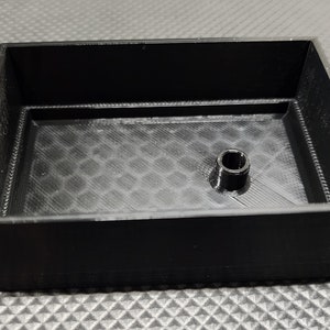 Peut inclure: Un r&eacute;cipient rectangulaire noir avec un cylindre central sur&eacute;lev&eacute;. L'int&eacute;rieur pr&eacute;sente un motif en nid d'abeille textur&eacute;. Les parois du r&eacute;cipient sont inclin&eacute;es, et le design est simple et fonctionnel.