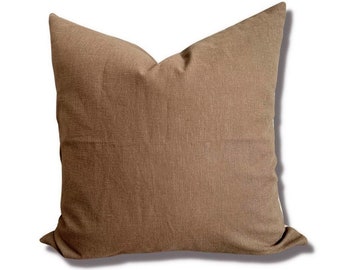 Könnte beinhalten: Ein braunes Leinen-Wurfsofa-Kissen mit quadratischer Form. Das Kissen ist aus einem weichen, strukturierten Stoff.