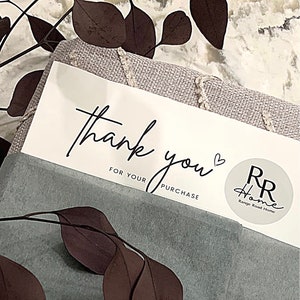 May include: A white thank you card with black script that says "thank you" with a heart symbol and "for your purchase". A round sticker with the text "RR Home Range Road Home" is in the bottom right corner.