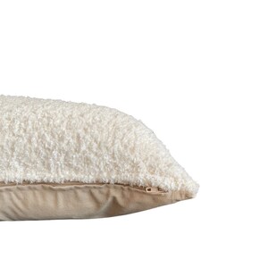 May include: A white fluffy pillow with a zipper closure and a beige fabric backing.