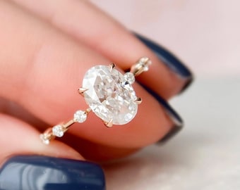 May include: A gold ring with a large oval-shaped diamond and smaller diamonds set in a delicate band.
