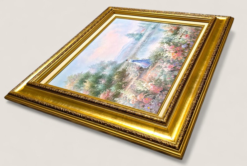 May include: A framed painting with a gold ornate frame. The artwork depicts a landscape scene with a figure in a blue dress. The painting features a variety of colors, including green, pink, and blue. The frame is a rich gold color.