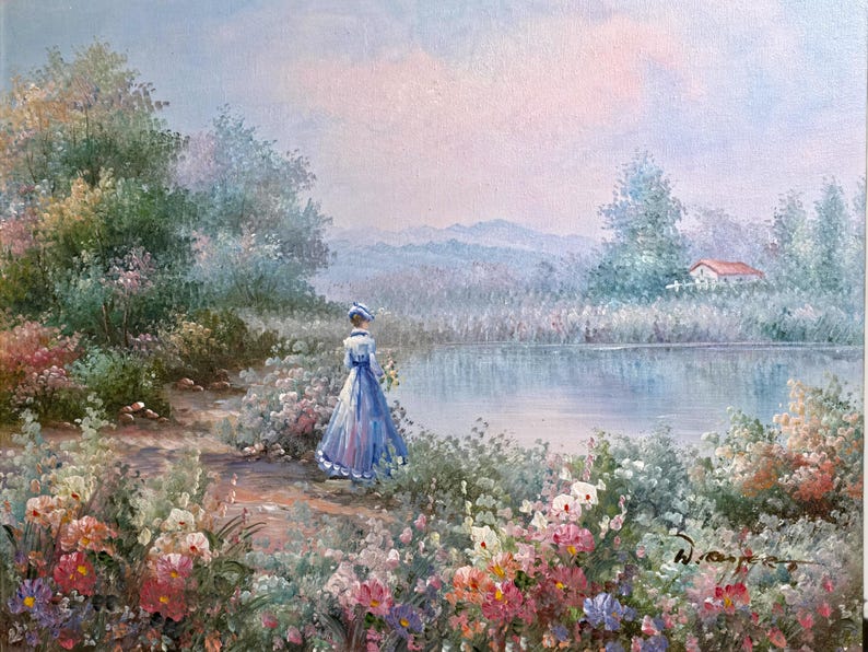 May include: Oil painting of a woman in a blue dress and hat standing near a lake. The scene is set in a garden with colorful flowers and lush greenery. A house with a red roof is visible in the distance.