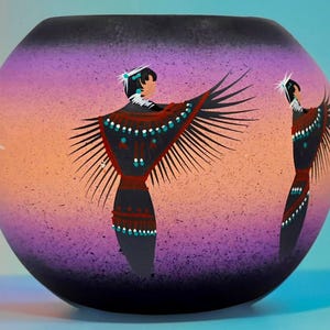 Könnte beinhalten: Eine runde, kugelförmige Vase mit einem Farbverlauf, der von tiefem Violett oben und unten zu einem sanften Orange in der Mitte übergeht. Die Oberfläche ist mit gemalten Figuren verziert, die dunkle Kleidung mit Fransen tragen.